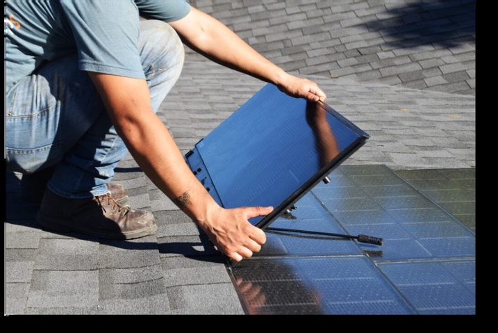 Installer placing a solar panel on a shingle roof