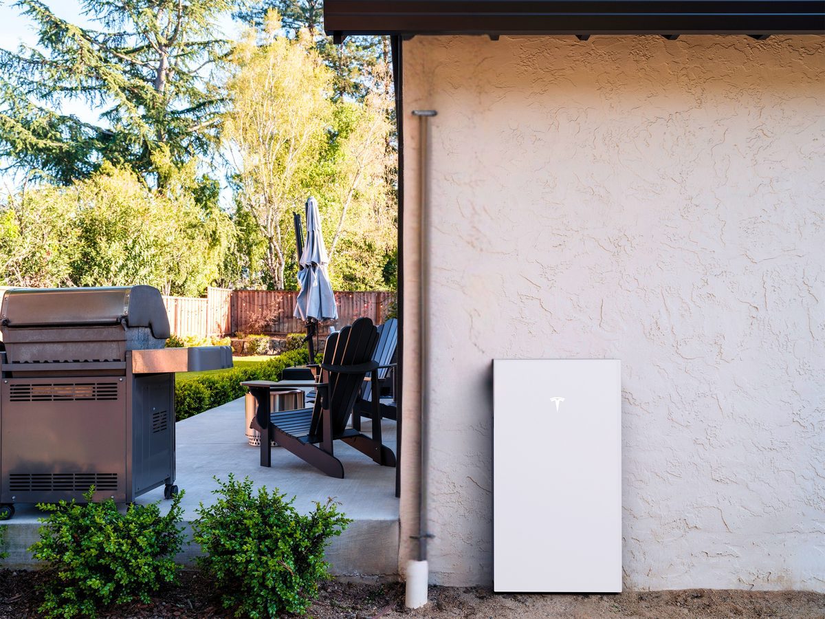 Home battery backup unit installed beside a residential patio