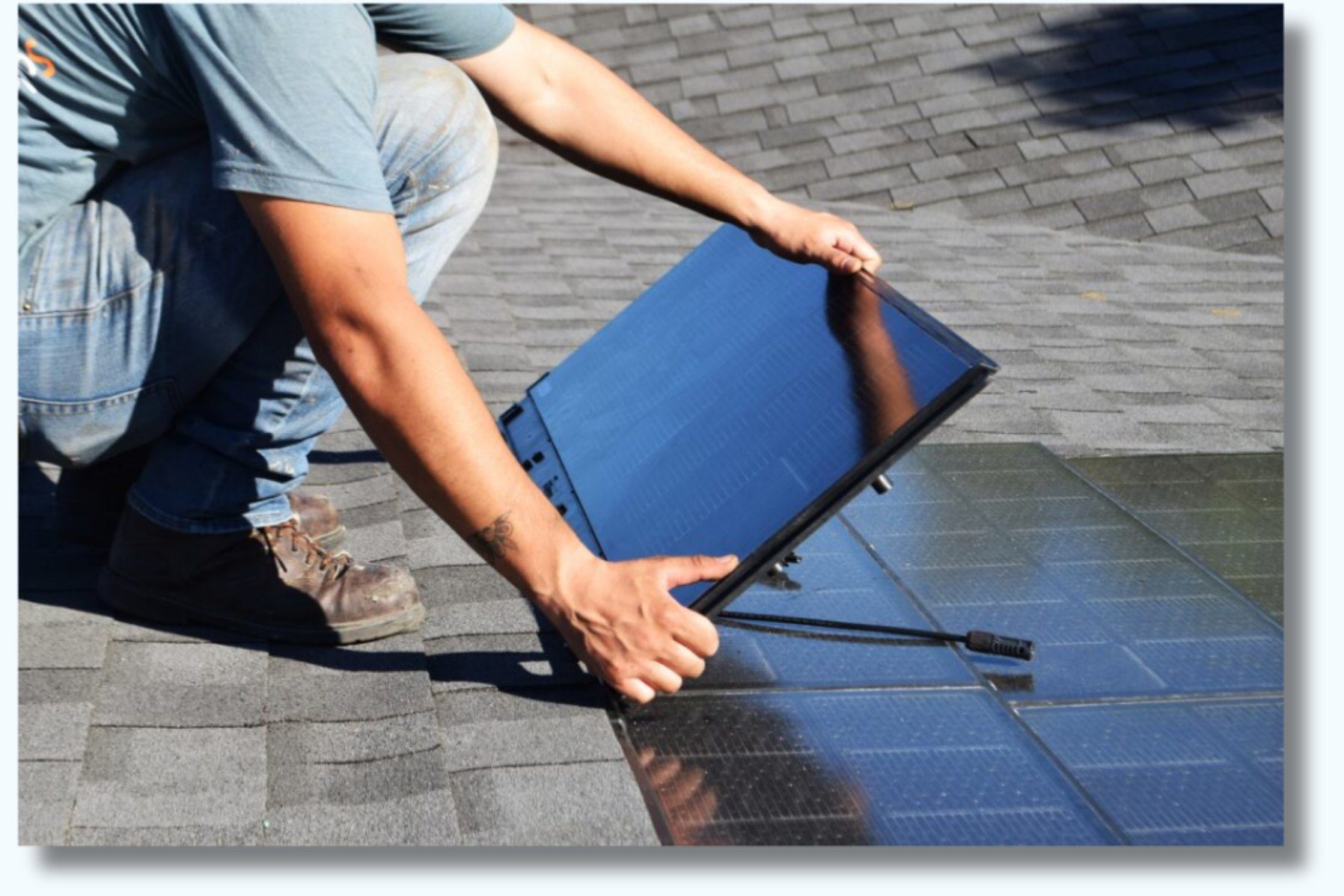 Installer placing a solar panel on a shingle roof
